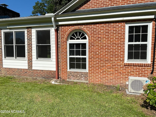 view of side of home featuring ac unit and a yard