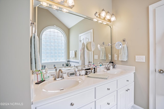 bathroom with vaulted ceiling, double vanity, and a sink