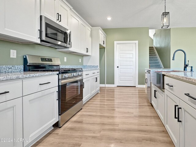 kitchen with light stone counters, light hardwood / wood-style flooring, stainless steel appliances, and white cabinets