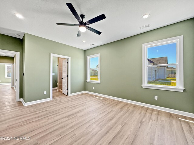 unfurnished bedroom featuring ensuite bath, ceiling fan, and light hardwood / wood-style flooring