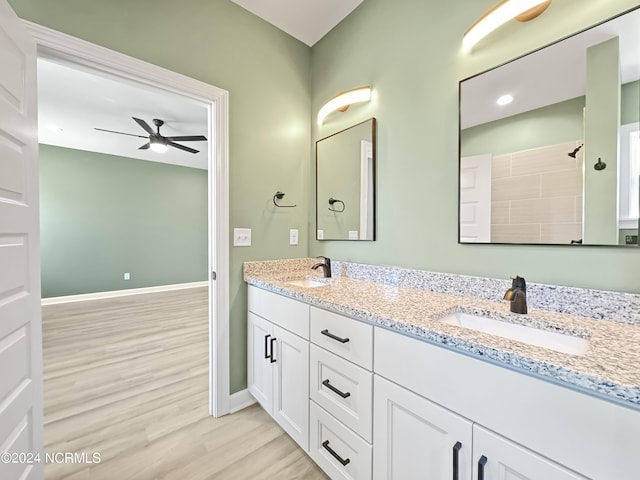 bathroom with double vanity, wood finished floors, a sink, and baseboards