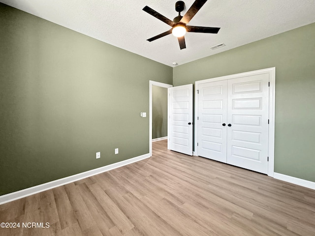 unfurnished bedroom featuring a textured ceiling, light wood-type flooring, ceiling fan, and a closet