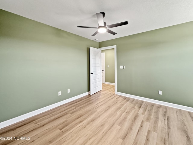 spare room with ceiling fan, light wood finished floors, and baseboards