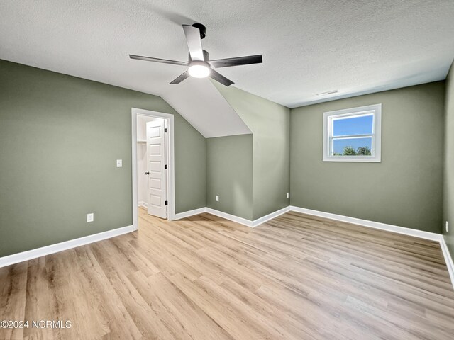 bonus room featuring ceiling fan, hardwood / wood-style flooring, lofted ceiling, and a textured ceiling