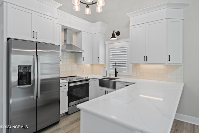 kitchen with light stone countertops, wall chimney exhaust hood, stainless steel appliances, sink, and light hardwood / wood-style floors