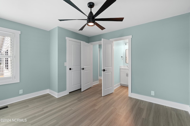 unfurnished bedroom featuring ensuite bathroom, light hardwood / wood-style flooring, and ceiling fan