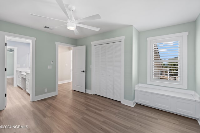 unfurnished bedroom with a closet, ensuite bath, ceiling fan, and light hardwood / wood-style floors