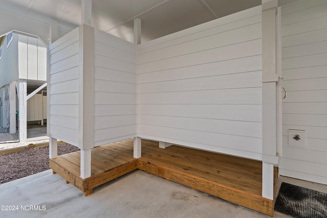 mudroom with concrete flooring and wooden walls