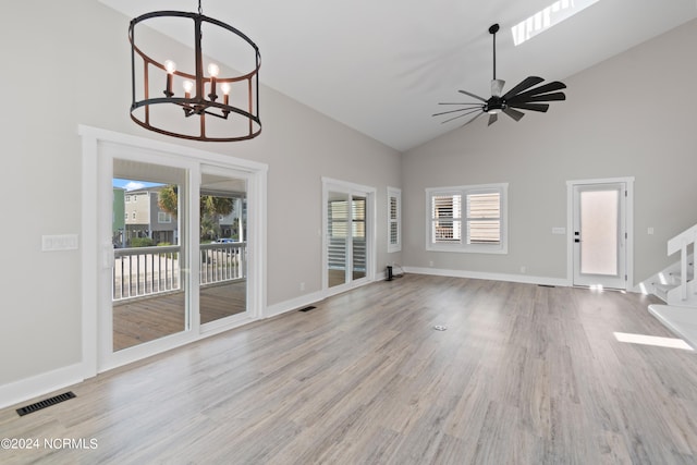 unfurnished living room with ceiling fan with notable chandelier, high vaulted ceiling, and light hardwood / wood-style flooring