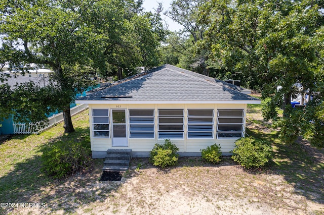 view of front of home with entry steps, roof with shingles, fence, and a front yard