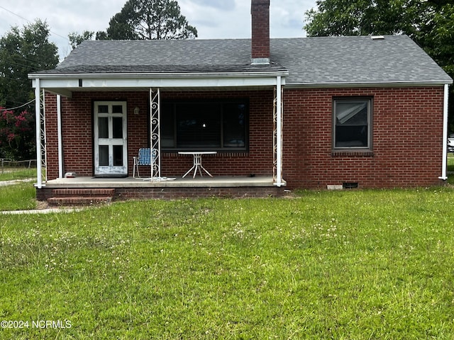 back of property featuring covered porch and a yard