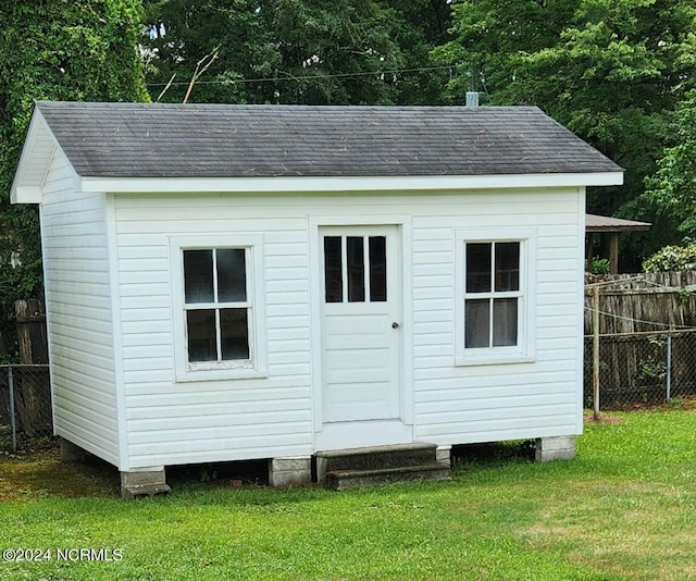 view of outbuilding featuring fence and an outdoor structure