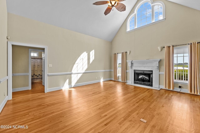 unfurnished living room featuring light wood-style flooring, a fireplace with flush hearth, a ceiling fan, high vaulted ceiling, and baseboards