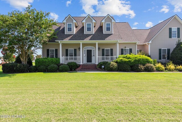 new england style home featuring a front yard and covered porch