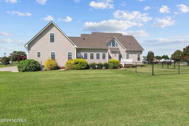 rear view of property with roof with shingles, fence, and a yard