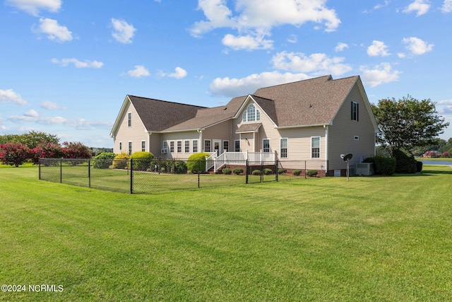 rear view of property with central AC, a lawn, and fence