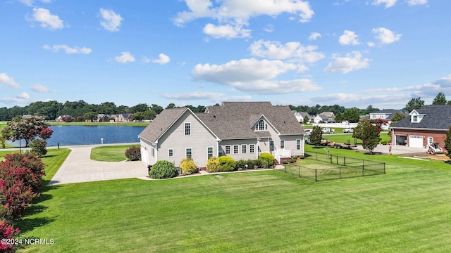 exterior space with a water view, fence, concrete driveway, and a yard