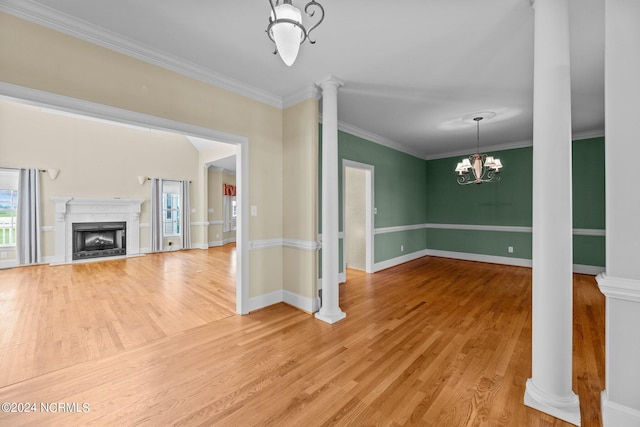 unfurnished living room with ornamental molding, decorative columns, light wood finished floors, and a premium fireplace