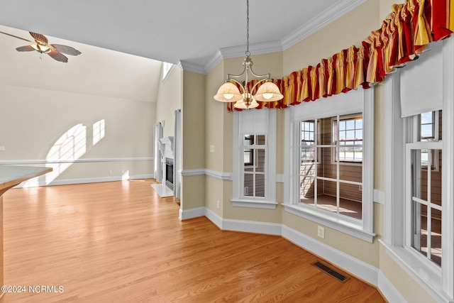 unfurnished dining area featuring a fireplace with flush hearth, visible vents, baseboards, ornamental molding, and light wood-type flooring