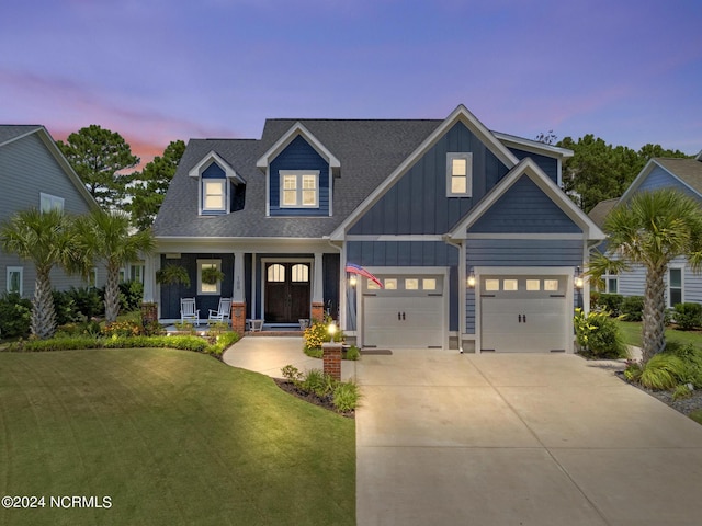 view of front facade featuring a porch, a yard, and a garage