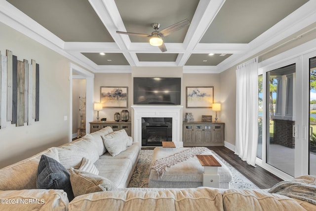 living room with beamed ceiling, dark hardwood / wood-style flooring, ornamental molding, coffered ceiling, and ceiling fan