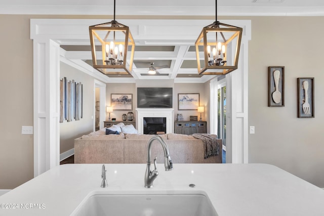 kitchen featuring hanging light fixtures, coffered ceiling, sink, and a chandelier