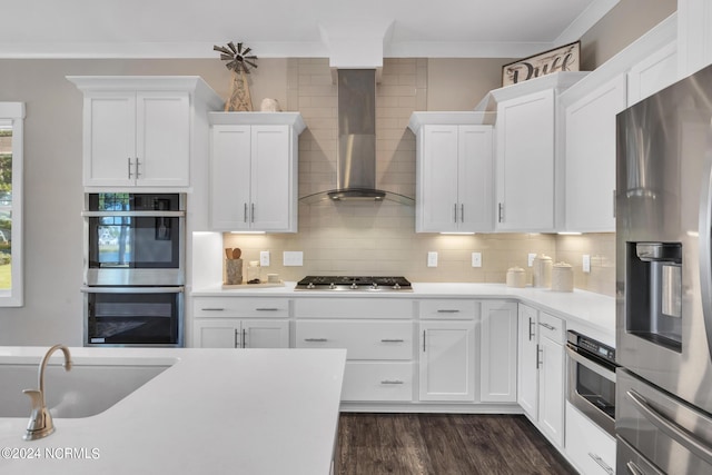 kitchen with wall chimney exhaust hood, tasteful backsplash, dark hardwood / wood-style floors, stainless steel appliances, and white cabinets