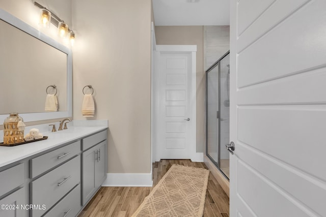 bathroom featuring a shower with door and vanity