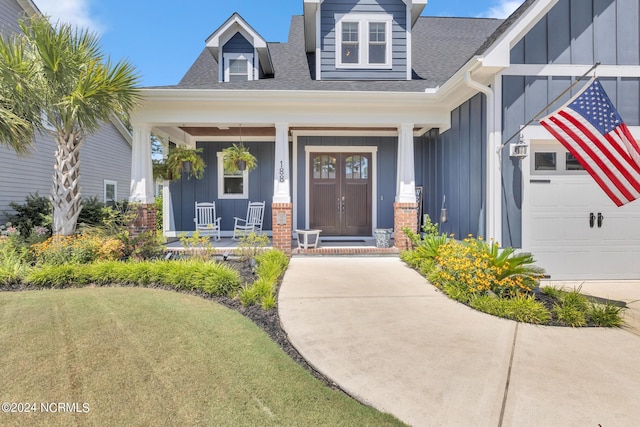 entrance to property with a garage, a yard, and covered porch