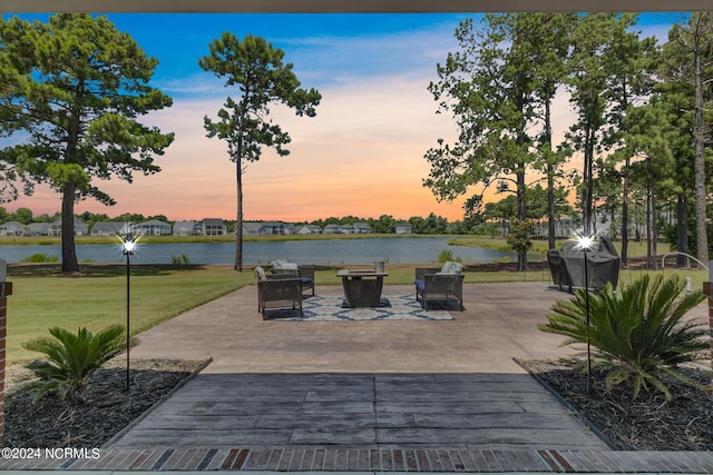 patio terrace at dusk with a water view and a lawn