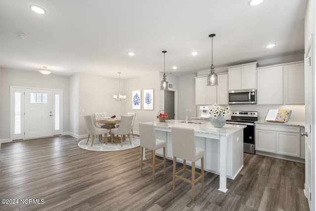 kitchen featuring dark wood-type flooring, stainless steel appliances, an island with sink, and white cabinetry