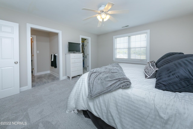 bedroom with baseboards, visible vents, a ceiling fan, carpet, and a spacious closet