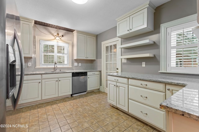 kitchen featuring stainless steel appliances, sink, backsplash, and light stone counters