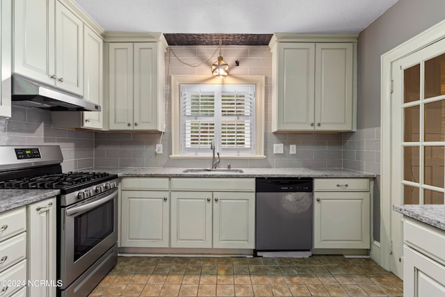 kitchen featuring sink, hanging light fixtures, light stone counters, stainless steel appliances, and cream cabinetry