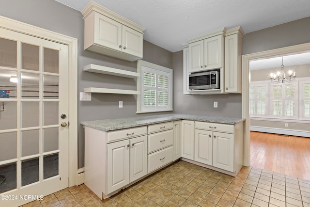 kitchen with an inviting chandelier, a baseboard radiator, and a healthy amount of sunlight