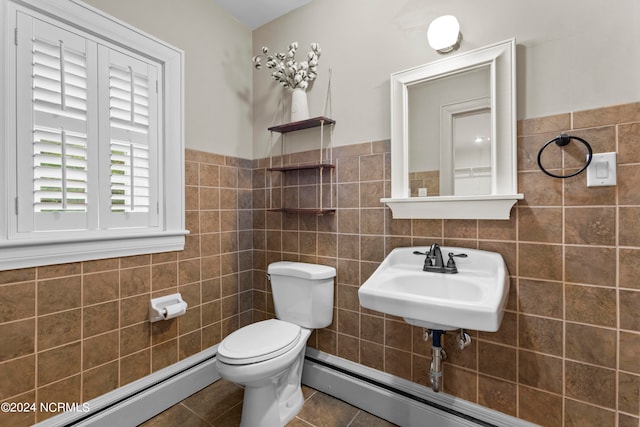 bathroom with tile patterned floors, toilet, sink, tile walls, and a baseboard heating unit