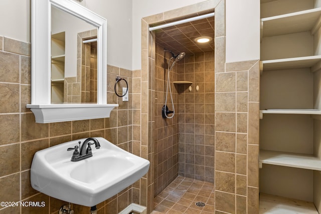 bathroom with tile walls, sink, and tiled shower