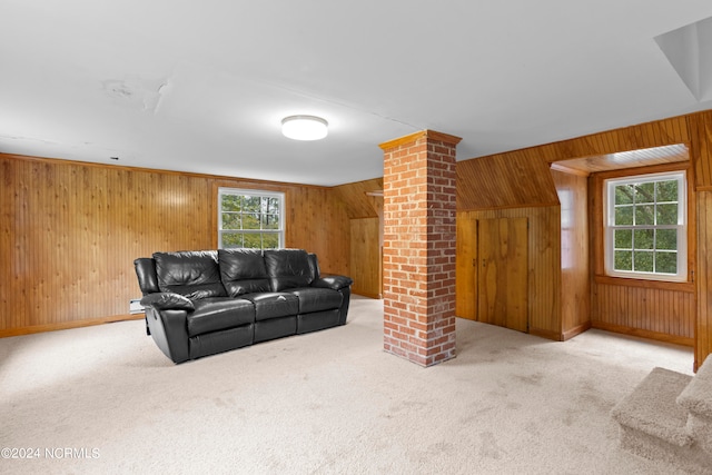 carpeted living room featuring decorative columns and wood walls