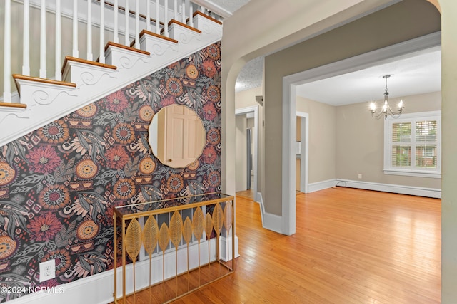 interior space featuring a baseboard heating unit, hardwood / wood-style floors, and an inviting chandelier