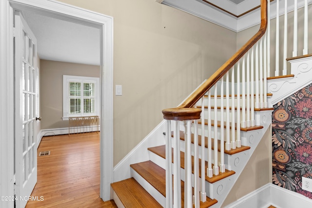 staircase featuring a baseboard heating unit and hardwood / wood-style floors