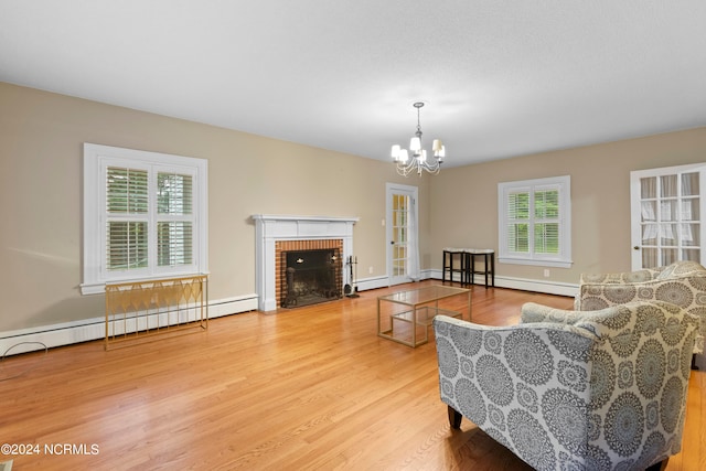 living room with light hardwood / wood-style floors, a fireplace, baseboard heating, and a wealth of natural light