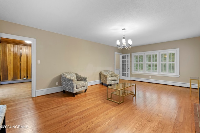 sitting room with a textured ceiling, an inviting chandelier, a baseboard heating unit, and light hardwood / wood-style flooring