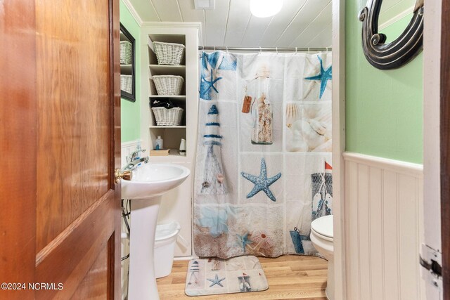 bathroom with toilet, crown molding, and hardwood / wood-style floors