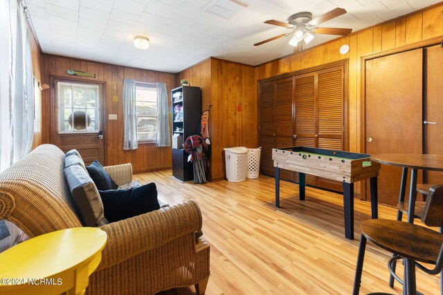 interior space with wooden walls, ceiling fan, and light hardwood / wood-style floors