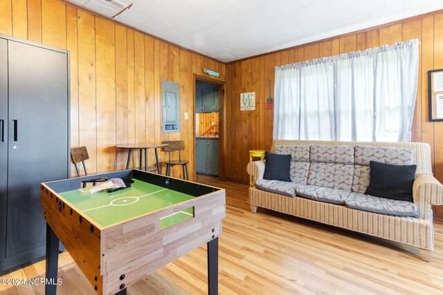 playroom with electric panel, wood walls, and light hardwood / wood-style flooring