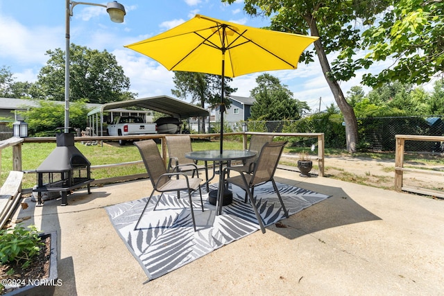 view of patio / terrace featuring outdoor dining space, fence, and a detached carport