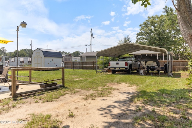 view of yard with dirt driveway, an outbuilding, fence, a shed, and a carport