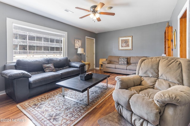 living area with ceiling fan, wood finished floors, visible vents, and baseboards