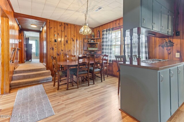 dining area with wood walls and light hardwood / wood-style flooring