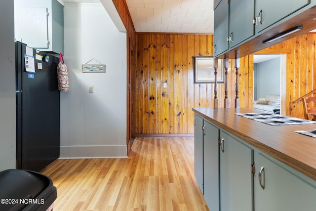 corridor with baseboards, light wood-type flooring, and wooden walls